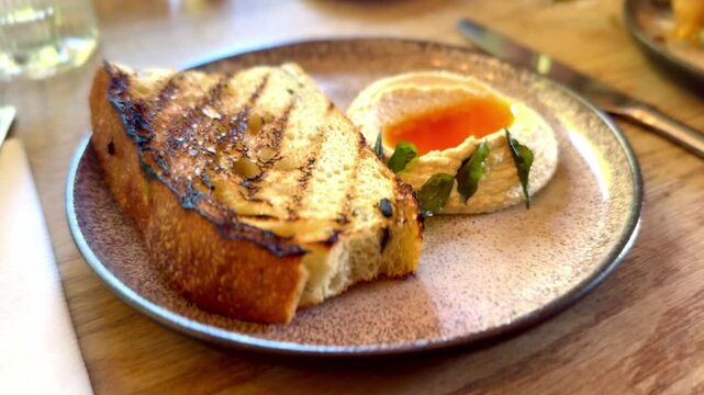 close up of toasted bread with side of hummus herbs and chili sauce appetiser