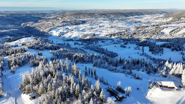 Aerial view of the snow-covered pine forests and ski slopes of the resort under a clear winter sky Les Rousses, Bourgogne-Franche-Comte, France.