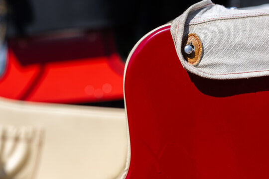 Close-up view of a red vintage car panel showing paint run defects and a beige canvas cover secured by a metal snap fastener under bright daylight.