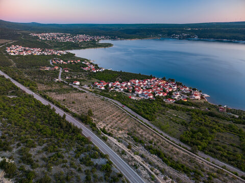 Aerial view of the Susnjar II settlement with red-roofed houses along the calm Novigrad Sea coast at twilight Krusevo, Zadarska zupanija, Croatia.