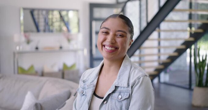 Woman on livingroom sofa turning to offframe cue smiling laughing touching face in denim jacket