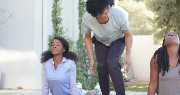 African American coach seeing posture issue fixing women on green mats on deck cueing chins