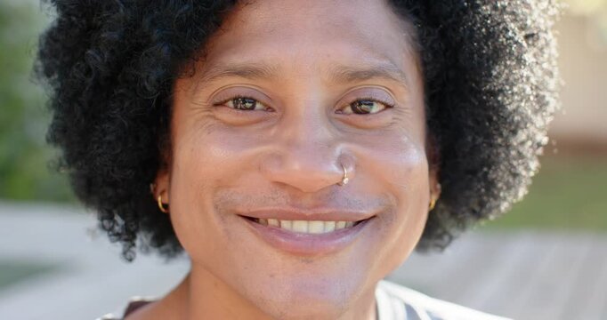 African American man reacting to off-camera cue, smiling, laughing on sunlit deck with nostril hoop