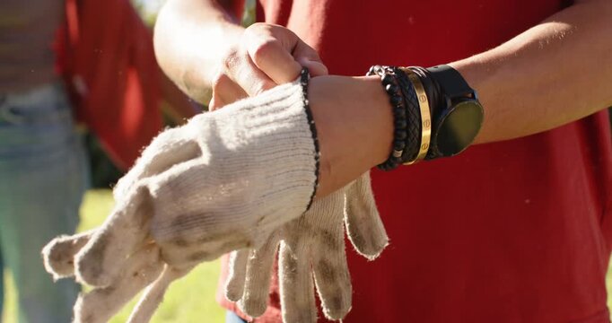 African American women putting on dirty knit work gloves, preparing for yard cleanup in sunlight