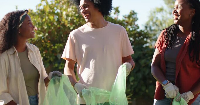 African American volunteers agreeing to start cleanup, prepping green bags, wearing gloves on lawn