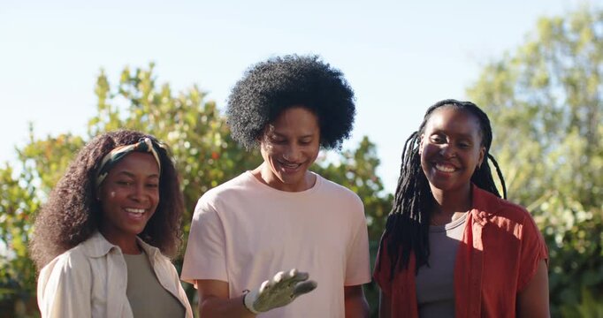 African American friends smiling donning gray gloves stacking hands over green bag for park cleanup