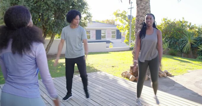 African American trio following leader giving cues, stepping, swinging arms on pool deck warming up
