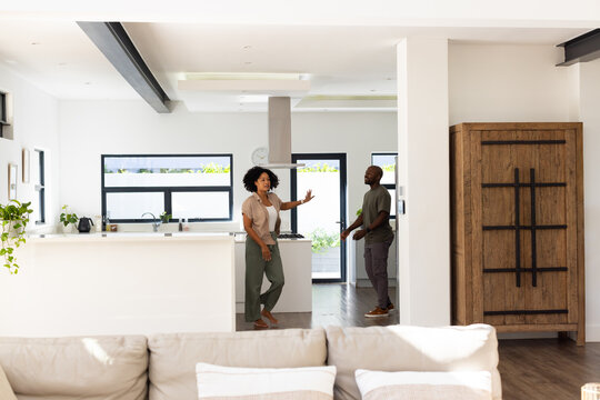 African American couple cooking and talking near kitchen island with cooktop and range hood