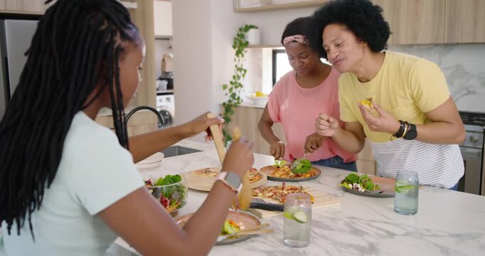 African American family starting with pizzas on wooden boards, plating and serving salad at counter
