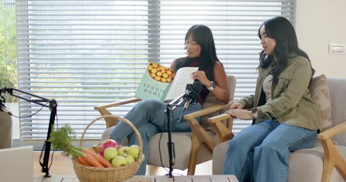 Asian, African American cohosts opening VEGGIE BOWL to SALADS in living room, talking mic capturing