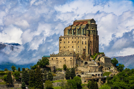 Sacra di San Michele abbey perched on Mount Pirchiriano at the entrance of the Susa Valley in spring, with clouds obscuring the Alpine summits in the background