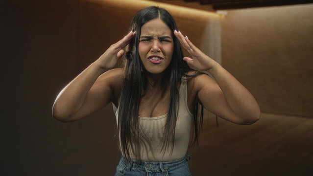 Hispanic woman pointing finger, hands on hips, leaning forward in a recording studio booth; anger confrontation tension.