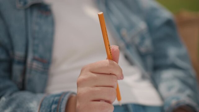 Outdoor playful finger movements. Youthful energy expressed through detailed hand actions. Closeup of hands holding pencil outdoors demonstrating energetic finger spins and youthful focus