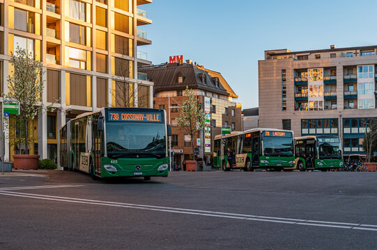 Green MBC public buses operating at the main transport hub in city at sunset in Switzerland.