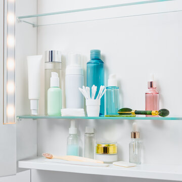 Skincare products are displayed on a shelf in a bathroom cabinet. Cosmetic storage in an apartment. Clean, bright, white interior