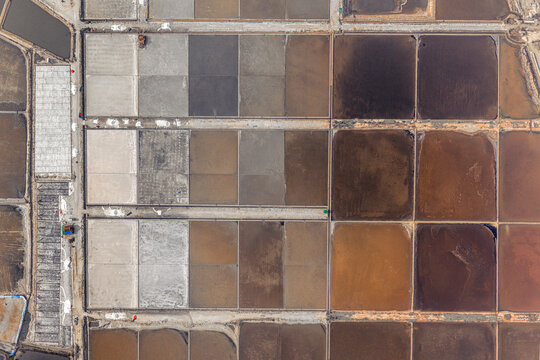 Aerial view of the geometric salt evaporation ponds showing various stages of salt crystallization in Dong Hai, Ninh Thuan, Vietnam.
