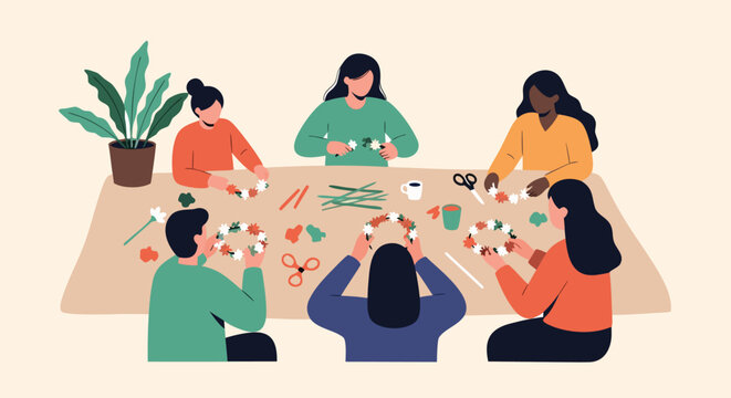 Group of diverse friends sitting around a large table and collaborating to create beautiful flower wreaths during a creative workshop.