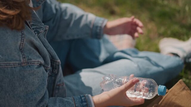 Female reviews picnic tools outdoors today. Woman thoroughly inspects her outdoor picnic accessories outside today. She methodically checks all her outdoor picnic supplies in fresh air today