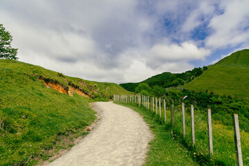 Fototapeta premium Curving Gravel Path Through Lush Green Hills