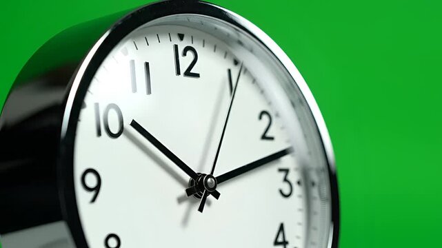 Closeup of a classic analog alarm clock face with green background.