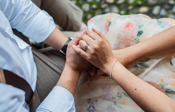 Primer plano de pareja tom&aacute;ndose de las manos con reloj elegante y vestimenta formal en momento rom&aacute;ntico