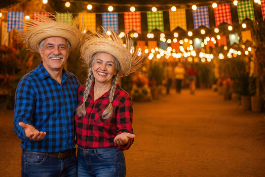 Middle-aged Brazilian mature couple, clothes from festa junina, inviting to the party, arraial, festa de s&atilde;o jo&atilde;o. boyfriend and girlfriend. Celebrating.frre space.