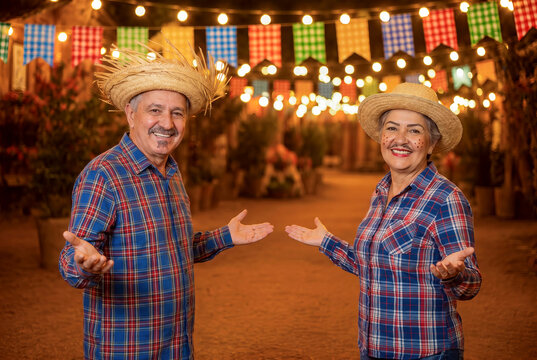 Middle-aged Brazilian mature couple, clothes from festa junina, inviting to the party, arraial, festa de s&atilde;o jo&atilde;o. boyfriend and girlfriend. Celebrating.frre space.
