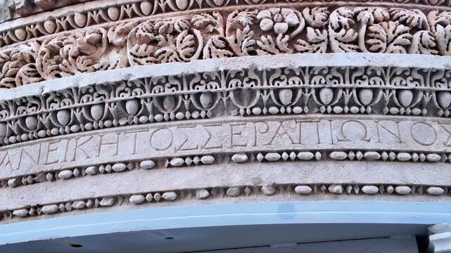 Detail of ancient roman stone architrave with carved greek inscription and decorative relief in antalya.