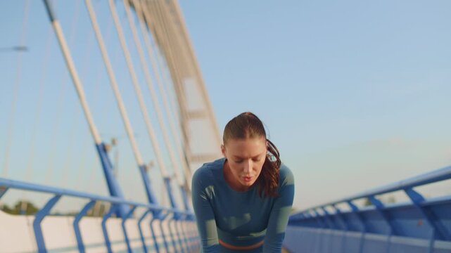 Exhausted female in sportswear wiping sweat from forehead after intense outdoor run