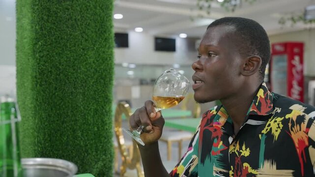 Man sipping wine at restaurant, colorful patterned shirt, ice bucket with bottle nearby, cozy table lighting, relaxed smile, romantic anticipation for date night, candid portrait vibe, urban bistro