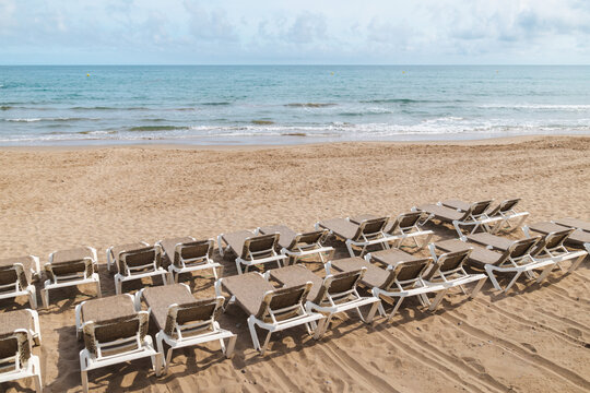 Empty beach loungers facing Mediterranean Sea on sandy beach in Sitges