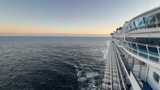 Epic Antarctica Cruise Ship At Sunset. Wide Shot Of Starboard Side of the Boat, Calm Ocean, Orange Sky with Glaciers and Snowcapped Mountains