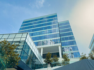 Obraz premium Modern office building stands tall against a clear sky with reflective glass panels showcasing a vibrant work environment in a busy city