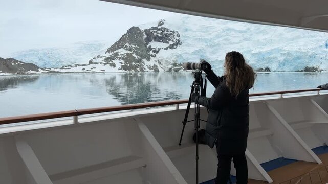 Female Photographer on Cruise Ship Deck Takes Photos with Telephoto Lens on Tripod. Hair Down Girl with Gloves Warm Coat Solo Female Travel Glacier