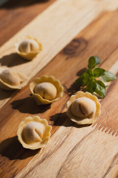 Close up of fresh cappelletti pasta showing filling detail on wooden surface, macro food