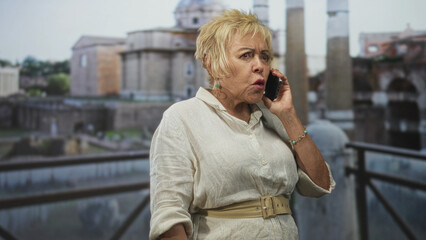 Obraz premium Woman holding smartphone to ear, hand on hip and gesturing on balcony by historic building; frustration urgency.