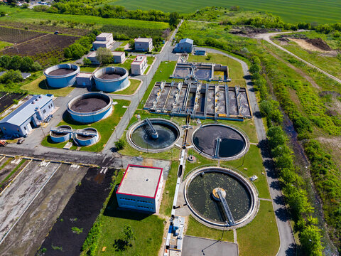 Water treatment facility in operation near agricultural fields with tanks and equipment used for processing wastewater during daytime