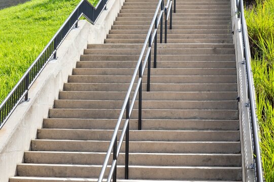 Concrete staircase with metal railings, and green grass on the sides