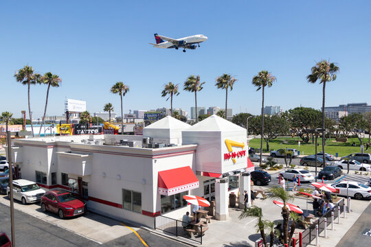 A Delta Air Lines Airbus A319 soars over an In-N-Out restaurant moments before landing at Los Angeles International Airport (LAX) - Los Angeles, California, USA