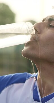 Thirsty, man and soccer player drinking water with break for practice, fitness and sports hydration. Athlete, person or footballer outdoor with bottle, electrolytes or refreshing liquid for wellness.