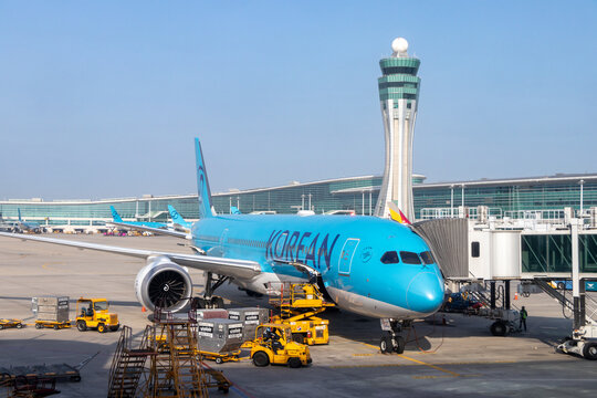 A Korean Air Boeing 787 parked at a gate with the air traffic control tower in the background at Seoul's Incheon International Airport - Seoul, South Korea