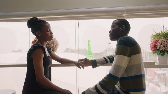 Intimate window handshake between couple at cafe, gentle reach across table with green bottle and bouquet, backlit silhouettes, emotional pause, tentative apology and hopeful reconnection in soft