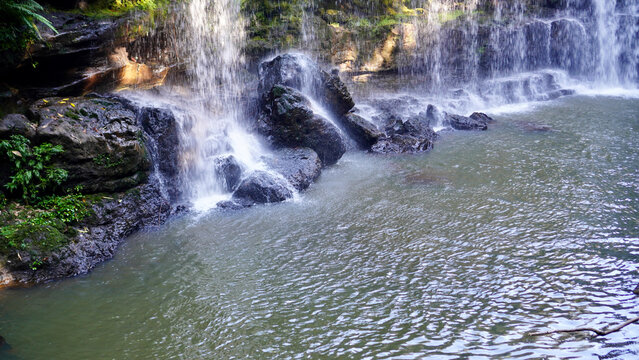 Tranquil river flowing between natural rock formations and lush green vegetation in a tropical forest landscape