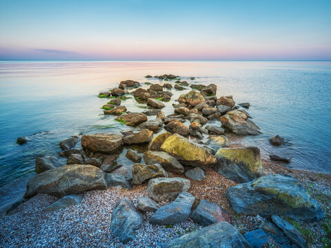group of stones in calm water of sea before evening twilights