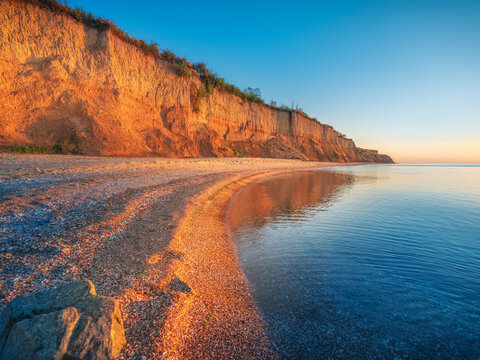 dramatic orange light of siring sun on the beach and cliff