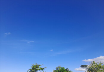 Fototapeta premium Beautiful and serene view of vast blue sky with white clouds and trees.