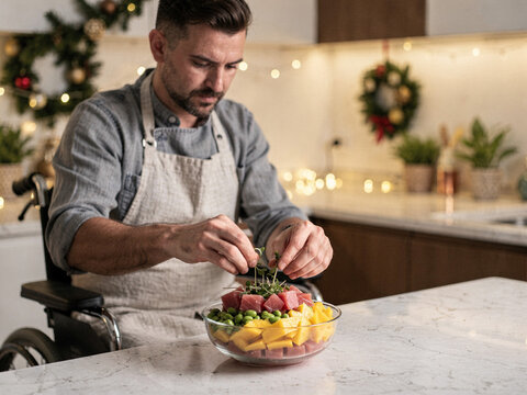 Man in Wheelchair Preparing a Healthy Poke Bowl in a Festive Christmas Kitchen