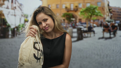 Fototapeta premium Woman holding money bag with dollar symbol on street cobblestone plaza, hand gripping bag strap; financial worry debt.