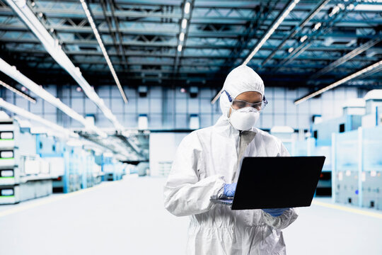 Technician man inspecting semiconductor production infrastructure with laptop, optimizing photolithography process, Worker trialing advanced materials for silicon wafers using notebook.