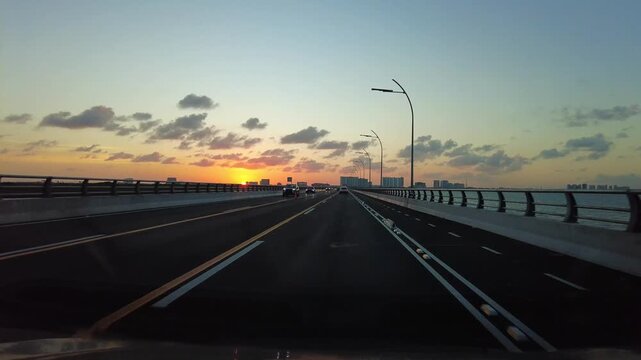 Dashcam POV driving over the new Nichupte Bridge in Cancun, Mexico at sunset. 4K real-time footage showcasing scenic lagoon views, golden hour sky